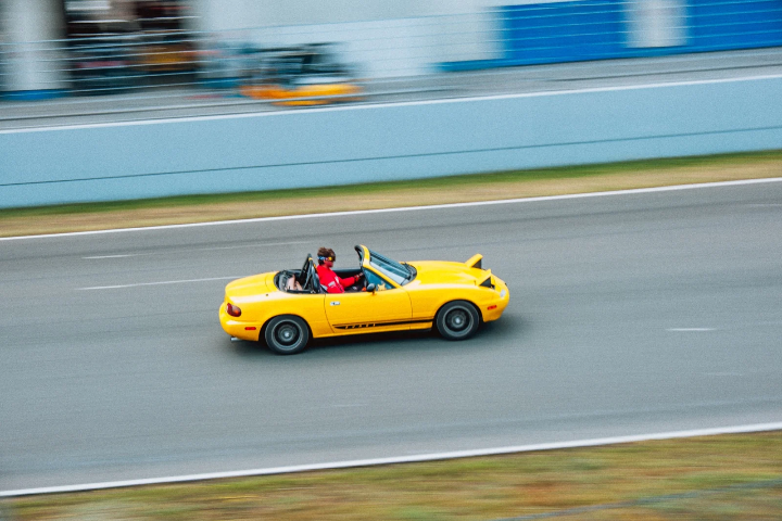 Yellow Mazda MX-5 passing the pit wall