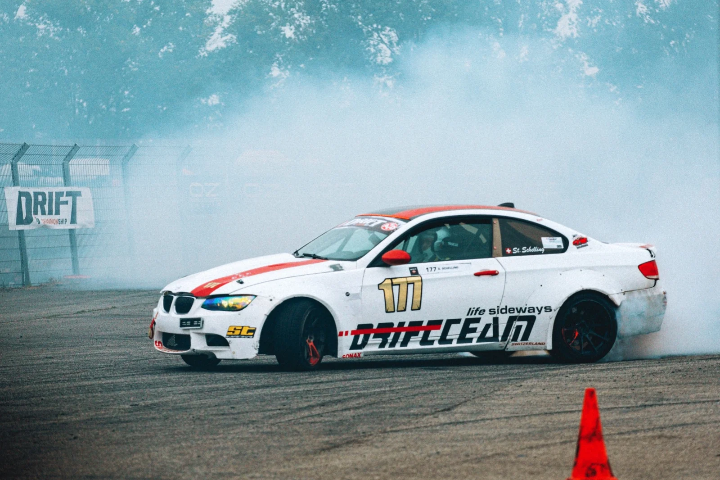 White BMW drift car emerging through tyre smoke