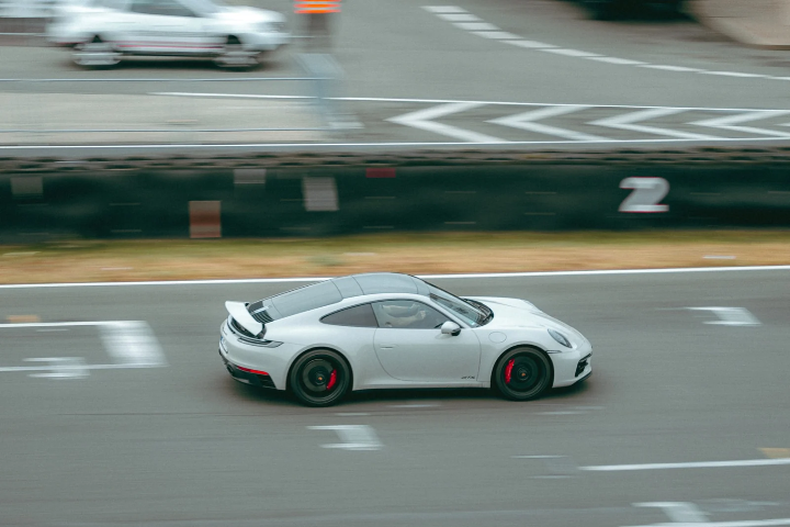 White Porsche 911 GTS on the straight, drift smoke behind