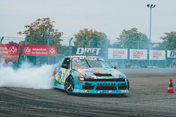 Blue drift car spinning smoke between the cones