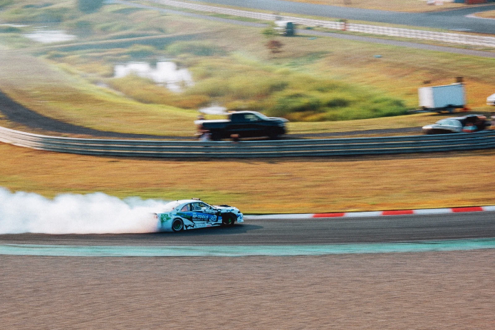 Drift car trailing smoke through a sweeping bend