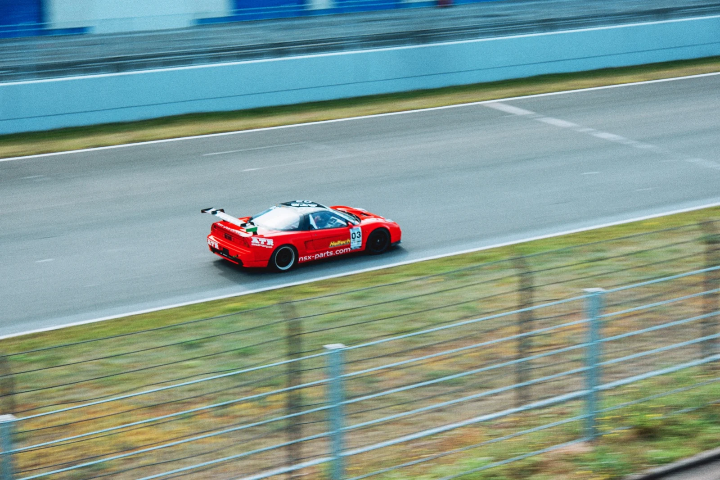 Red Honda NSX race car passing at speed