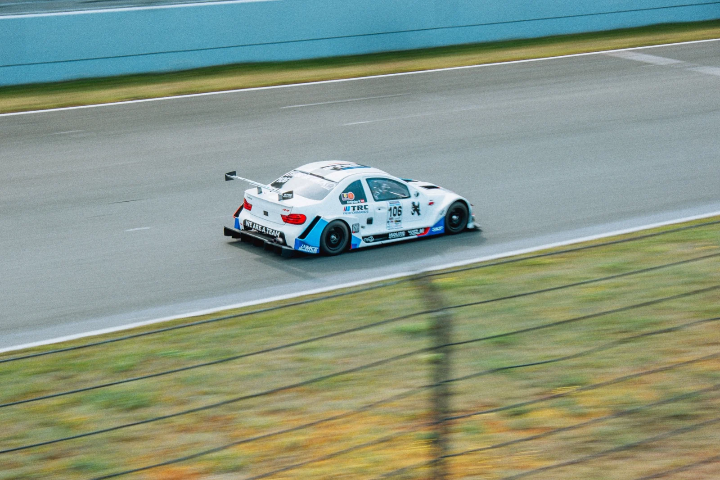 White-and-blue race car, rear three-quarter on the straight
