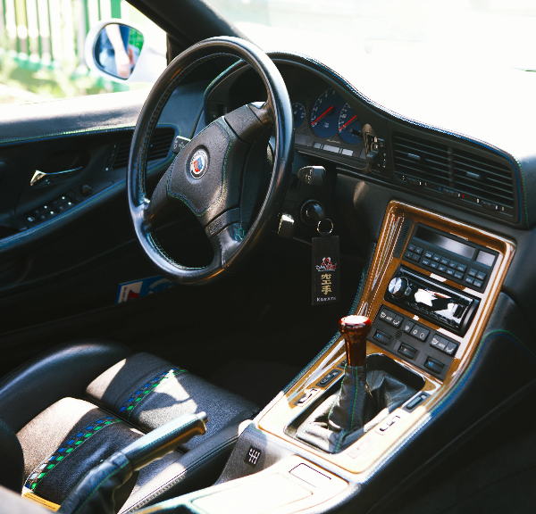 Classic car interior with leather steering wheel, wooden centre console and manual gear lever