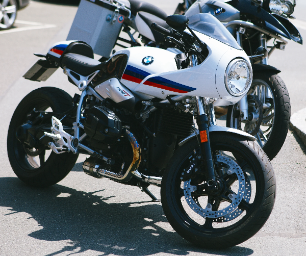 White BMW boxer motorcycle with blue and red motorsport stripes, round headlight and exposed engine
